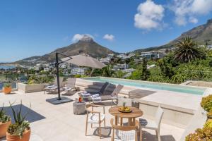 un patio con tavolo e sedie e una piscina di Azamara Luxury Villa - Camps Bay a Città del Capo
