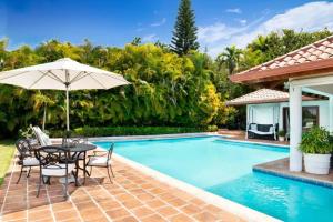 een patio met een tafel en een parasol naast een zwembad bij Los Lagos 19- Golf and Lake View 5-Bedroom Villa in La Romana