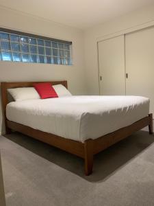 a bedroom with a large bed with a red pillow at Quayside Luxury Apartments in Whakatane