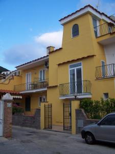 a yellow house with a car parked in front of it at Albergo Macrì in Ischia