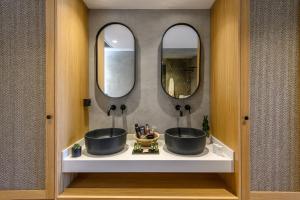 a bathroom with two sinks and two mirrors at Stella Palace Aqua Park Resort in Hersonissos