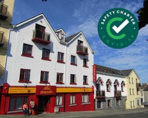 Un grand bâtiment blanc avec des personnes debout devant lui dans l'établissement Sleepzone Hostel Galway City, à Galway