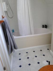 a bathroom with a white tub and a white tile floor at Detached two bedroom cottage in Riverchapel