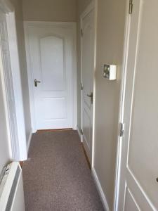 an empty hallway with a white door in a room at Detached two bedroom cottage in Riverchapel