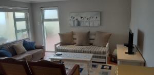 a living room with a couch and a table at Meerhuis Cottage in Langebaan