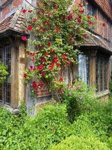 an old house with red flowers on the side of it at Langshott Manor - Luxury Hotel Gatwick in Horley