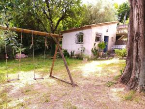 an empty swing set in a yard next to a tree at Maison Le Retour in Le Rouret