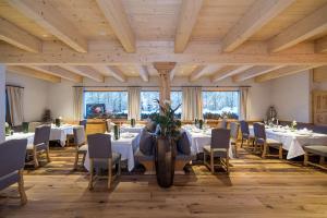 a dining room with white tables and chairs at Kolfuschgerhof Mountain Resort in Colfosco