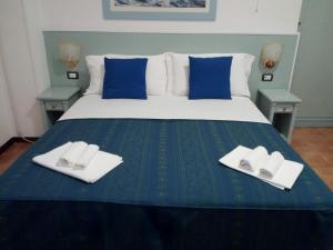 a bed with two white plates and blue pillows at Hotel Mercede 2 in San Felice Circeo