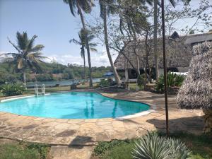 a swimming pool in a yard with palm trees at Sunset Fastcare luxury Apartments in Mombasa