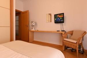 アルマカオ・デ・ペラにあるApartamento Mouraのベッドルーム(ベッド1台、デスク、テレビ付)