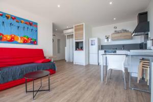 a living room with a red couch and a kitchen at Très beau T2 climatisé refait à neuf, vue mer panoramique exceptionnelle à 120m à pied de la plage in La Ciotat