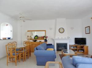 a living room with blue chairs and a fireplace at Casa Rosa Floresta in Luz