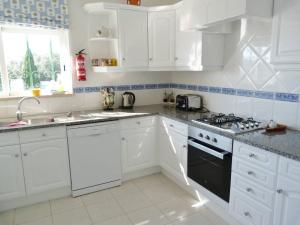 a white kitchen with white cabinets and a stove top oven at Casa Rosa Floresta in Luz