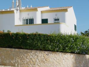 a white building behind a stone wall with flowers at Casa Rosa Floresta in Luz
