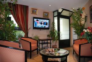 a living room with chairs and a tv on the wall at Hôtel Transcontinental in Paris