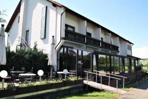 a building with tables and umbrellas in front of it at Hotel Waldschlösschen in Dankmarshausen