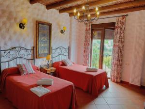 2 camas rojas en una habitación con ventana en Villa La Posada, en Canillas de Albaida