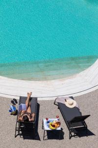 una mujer tendida en una silla de jardín junto a una piscina en Villa Masetta - Luxury Suites, en Mondello