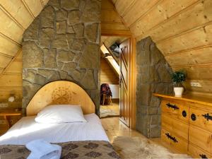 Cama en habitación con pared de piedra en Pensjonat u Ani, en Zakopane