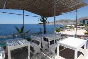 una mesa y bancos en la playa con el océano en Blue Bay Hotel, en Sarandë