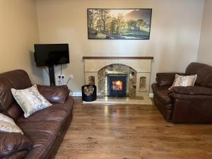 a living room with two couches and a fireplace at Ketty's Cottage in Rosslea