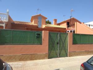 a house with green gates in front of it at Casa del Poniente Playa y Terraza in Lepe
