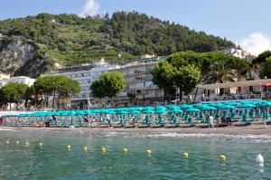 a beach with chairs and umbrellas and a hotel at Hotel Panorama in Maiori