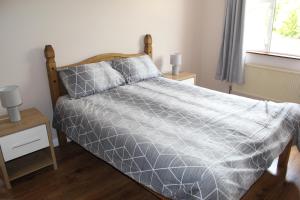 - un lit avec une couette grise dans une chambre dans l'établissement Ketty's Cottage, à Rosslea