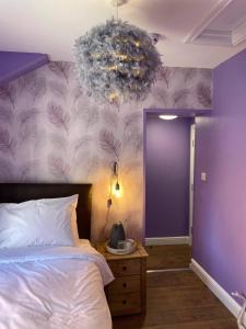 ein Schlafzimmer mit einem Bett und einer lila Wand in der Unterkunft The Black Swan Hotel in Scarborough