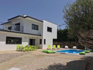 Villa con piscina y sillas verdes en Casa Verde en Feteira