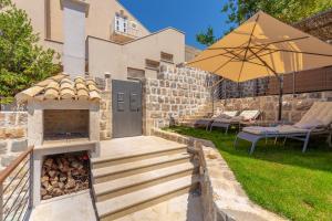 a backyard with an outdoor grill and an umbrella at Hedera Estate, Hedera A54 in Dubrovnik