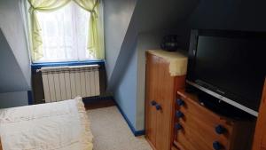 a living room with a television on a dresser and a window at Święty Spokój in Tuchlin