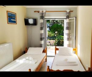 two beds in a room with a window and a television at Paraskevi Apartments in Lefkada Town