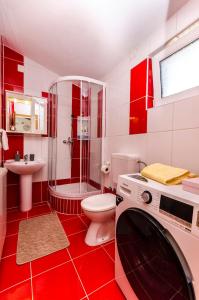 a red and white bathroom with a toilet and a sink at Apartments Ante in Vodice