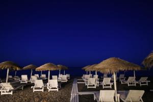 a group of chairs and umbrellas on the beach at night at Seaside Breeze in Kamari
