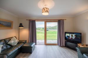 a living room with a couch and a tv at Capercaillie Cottage in Crianlarich
