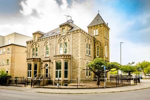 a large brick building with a clock tower at Stay Suites Huddersfield in Huddersfield