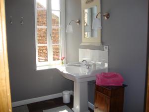 uma casa de banho com um lavatório branco e uma janela em La Cour des Carmes em Arras