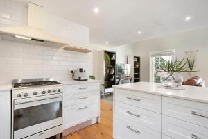 cocina con armarios blancos y fogones en Magnolia Cottage, en Ciudad del Cabo