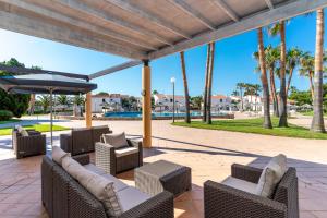 a patio with chairs and an umbrella and palm trees at Apartamentos Vistapicas in Cala en Blanes