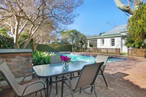 een terras met een tafel en stoelen en een zwembad bij Magnolia Cottage in Kaapstad