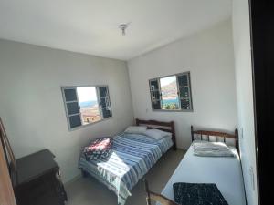 a small bedroom with a bed and a small window at Casa do Disco Voador in São Thomé das Letras