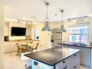 cocina con armarios blancos y encimera negra en Stunning 6 bedroom Farmhouse in Hellingly en Hailsham