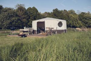 a tent with a table and a grill in a field at Home Farm Glamping in Elstree