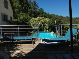 a pool with two chairs and a person in the water at Les bois d'ormes in Bessey-en-Chaume