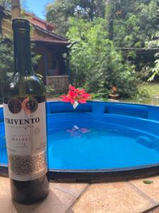 a bottle of wine sitting next to a swimming pool at Sítio Macaúbas do Moinho in Alto Paraíso de Goiás