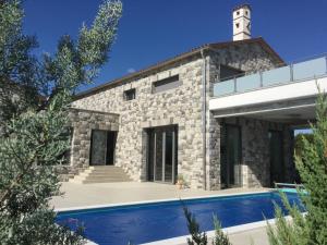 une maison en pierre avec une piscine en face de celle-ci dans l'établissement Villa Lavanda in Kriz Sezana with private swimpool, à Sežana