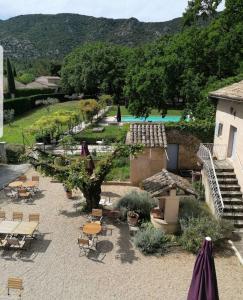 einen Innenhof mit Tischen und Stühlen und einen Pool in der Unterkunft La Bastide Du Bois Breant in Maubec