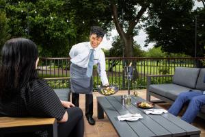a man in an apron holding a plate of food at Herbert Park Hotel and Park Residence in Dublin